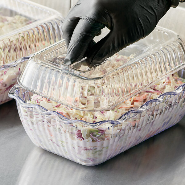 A person in black gloves using a clear plastic Choice deli container to serve food.