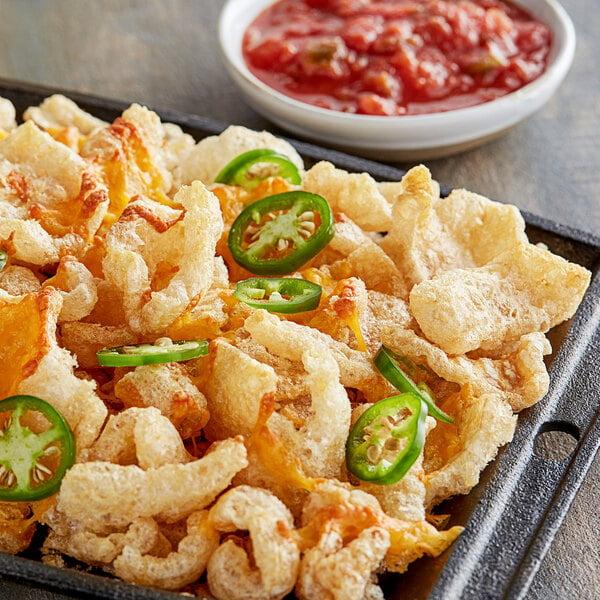 A plate of Goya Chicharrones with red salsa.