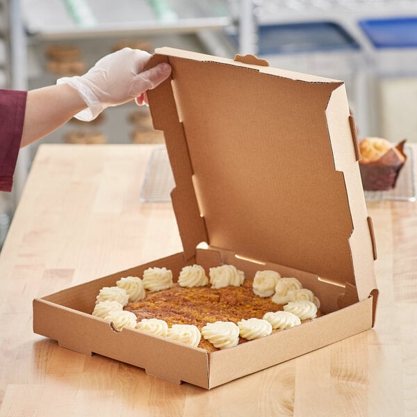 A person holding a Choice Kraft bakery box on a table with a cake inside.