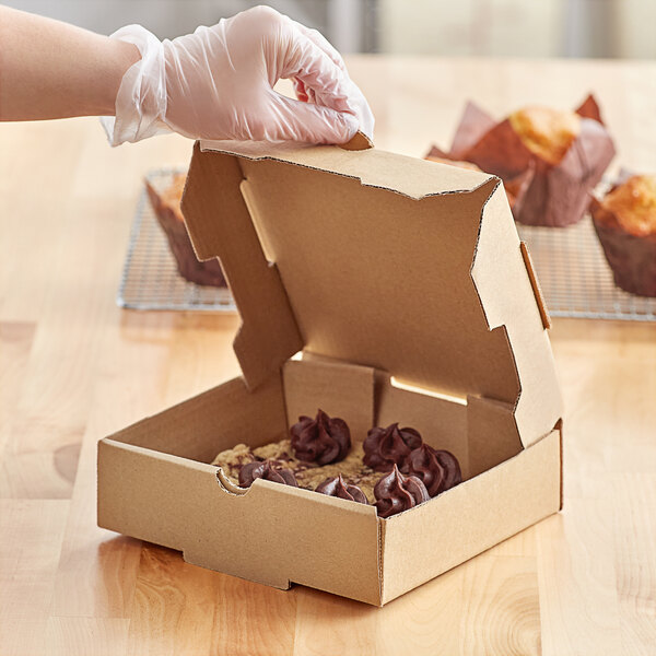 A person wearing a plastic glove opening a Choice Kraft bakery box to put food inside.