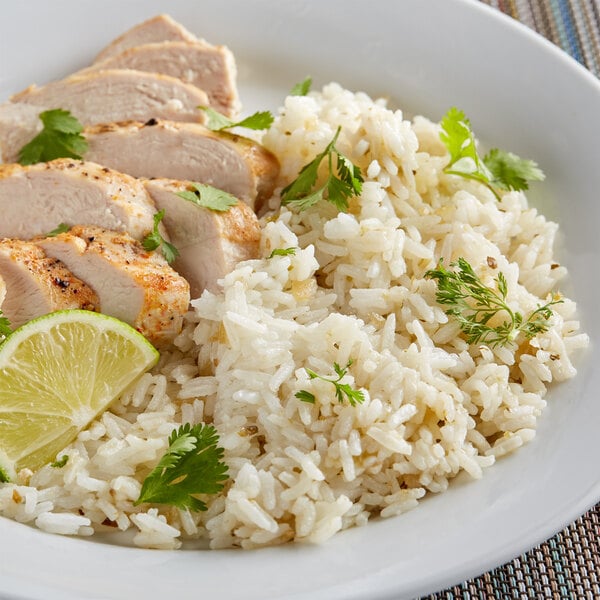 A plate of rice and chicken with lime wedges on the side.