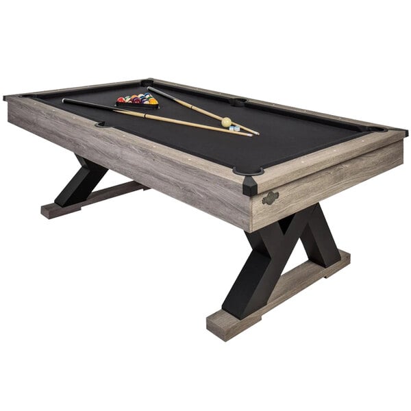 An American Legend Kirkwood pool table with a black and rustic grey wood finish with cue sticks and balls on it.
