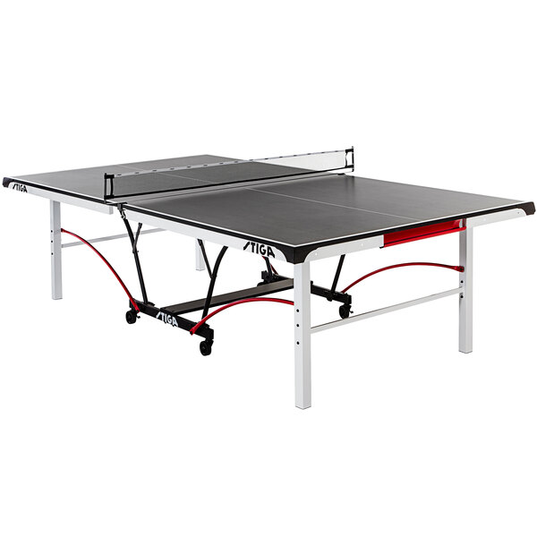 A Stiga table tennis table with a black and red top and net on wheels.