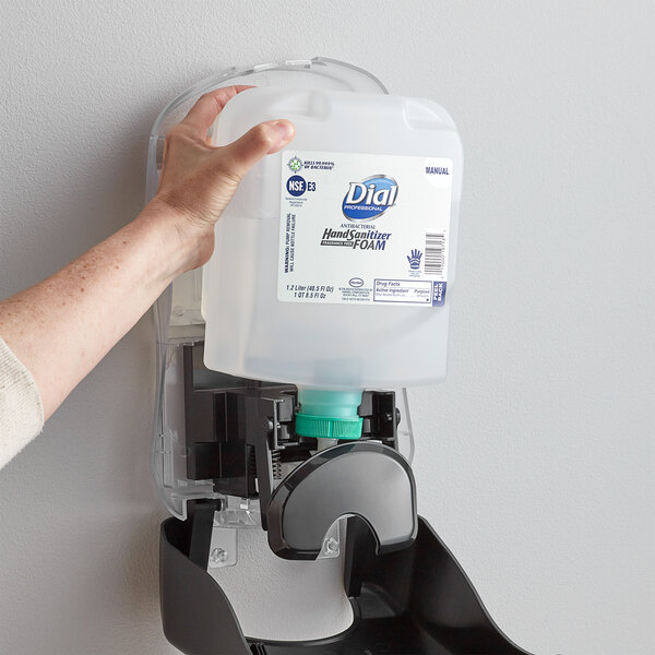 A hand reaching out to a Dial foam hand sanitizer refill container.