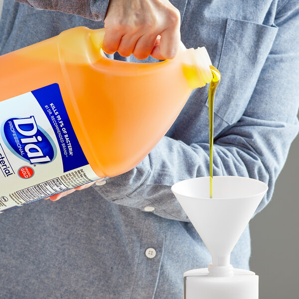 A person pouring liquid into a large bottle using a funnel.