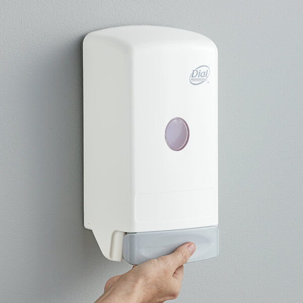 A hand using a white Dial manual liquid hand soap dispenser.