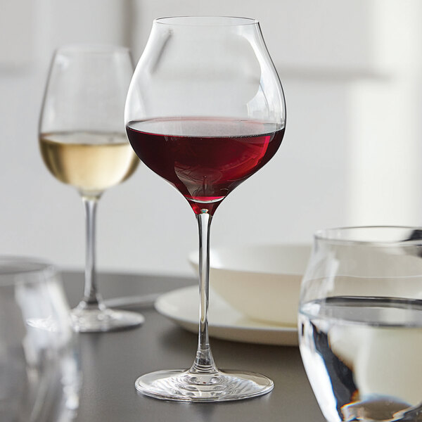 A Chef & Sommelier Villeneuve Burgundy wine glass filled with red wine on a table.