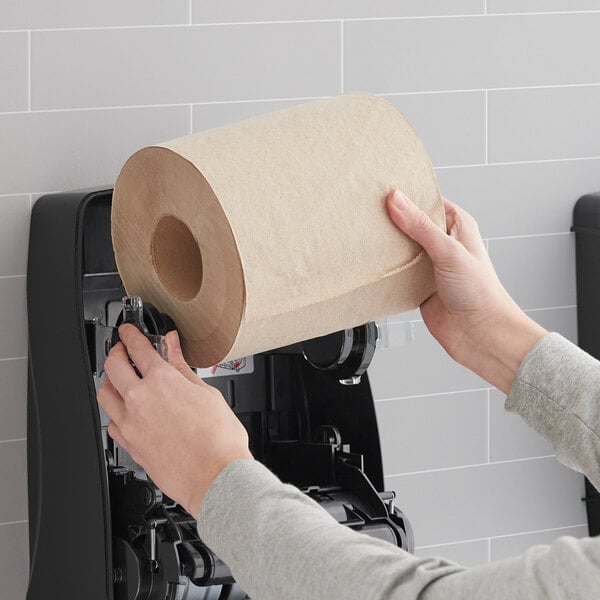 A person holding a Lavex Select natural kraft paper towel roll.