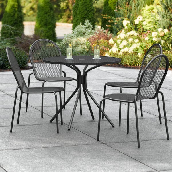 A black Lancaster Table & Seating outdoor table with four chairs on a patio.