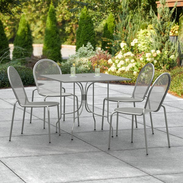 A Lancaster Table & Seating Harbor Gray outdoor table and chairs on a patio.