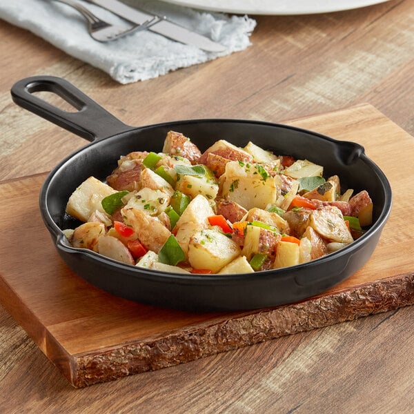 An American Metalcraft faux cast iron fry pan server with food on a table.