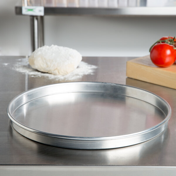 An American Metalcraft heavy weight aluminum round pizza pan on a counter.