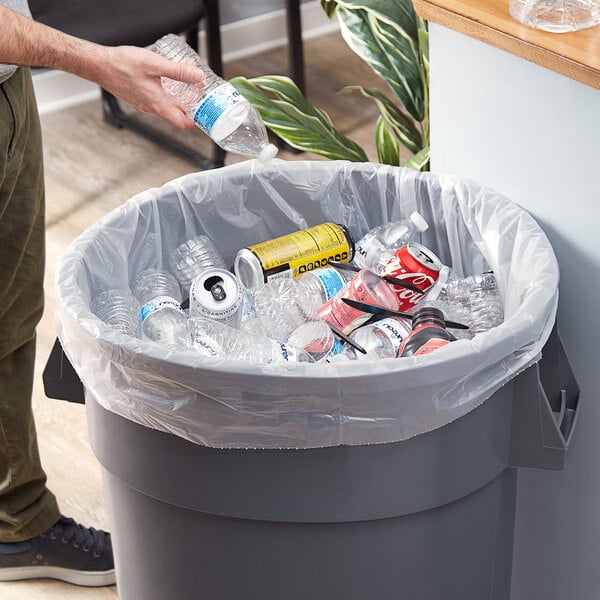 A man putting plastic bottles into a yellow and blue Lavex Li'l Herc trash bag.