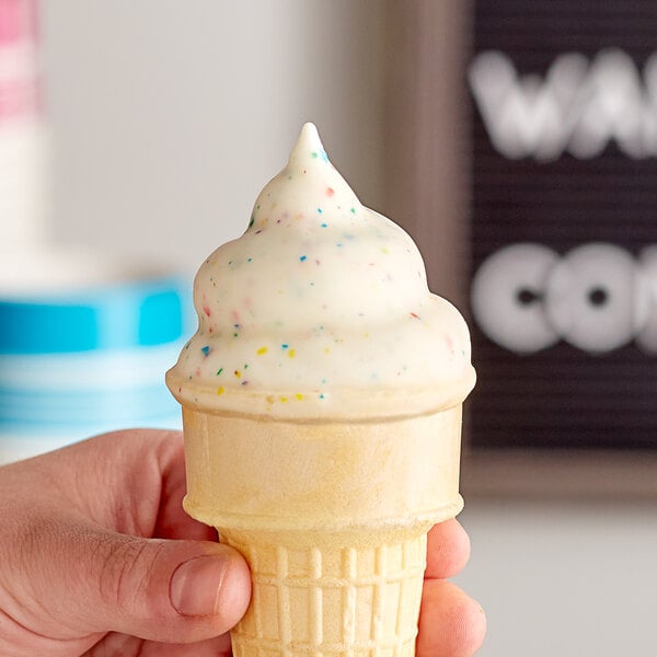 A person holding a J. Hungerford Smith ice cream cone with sprinkles.