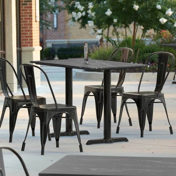 A Lancaster Table and Seating rectangular outdoor dining table with a grey surface and white edge on a patio.