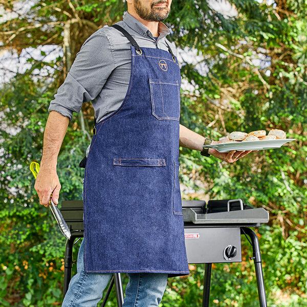A man wearing an Outset denim apron holding a plate of food.
