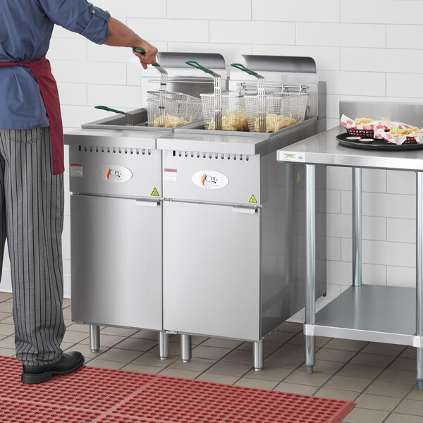 A man standing next to a Cooking Performance Group stainless steel floor fryer.