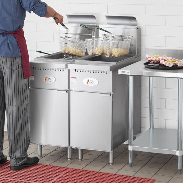 A man standing in front of a Cooking Performance Group stainless steel floor fryer.