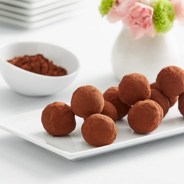 A white plate of chocolate truffles dusted with Cacao Barry Extra Brute Cocoa Powder.