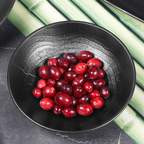A black matte melamine bowl with an embossed design filled with cranberries.