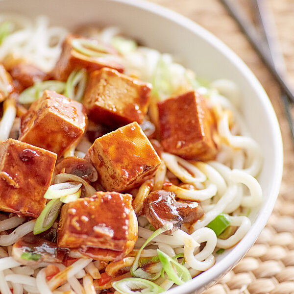 A bowl of noodles with tofu and green onions topped with Lee Kum Kee Medium-Hot Sichuan-Style Mabo Tofu Sauce.