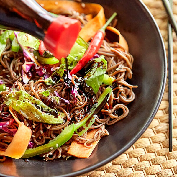 A bowl of noodles with vegetables and Lee Kum Kee gluten-free dark soy sauce.