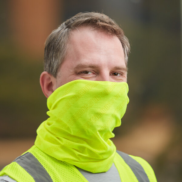 A man wearing a yellow vest and a lime green Ergodyne Multi-Band as a face covering.