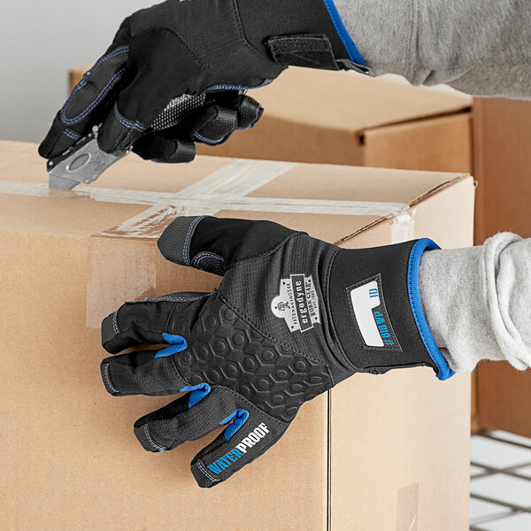A person wearing Ergodyne ProFlex thermal waterproof work gloves holding a box with scissors.