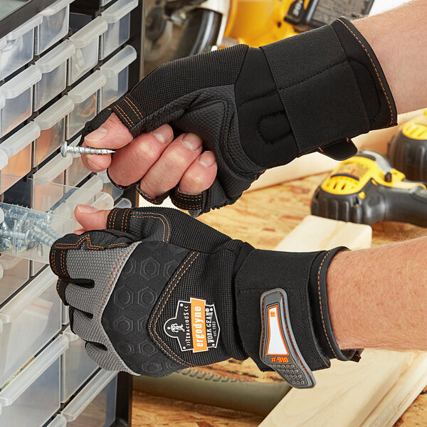 A man wearing Ergodyne heavy duty work gloves holding a screw in a drawer.