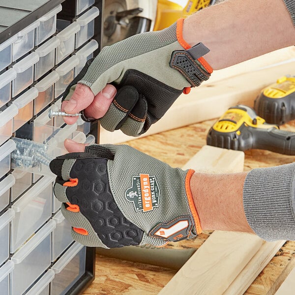A person wearing Ergodyne heavy-duty work gloves holding a screw.
