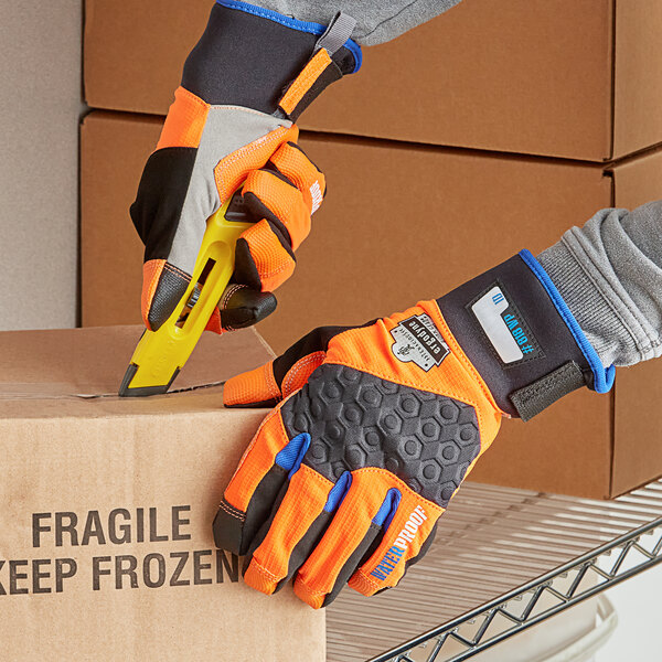 A person wearing Ergodyne ProFlex thermal waterproof work gloves cuts a box.