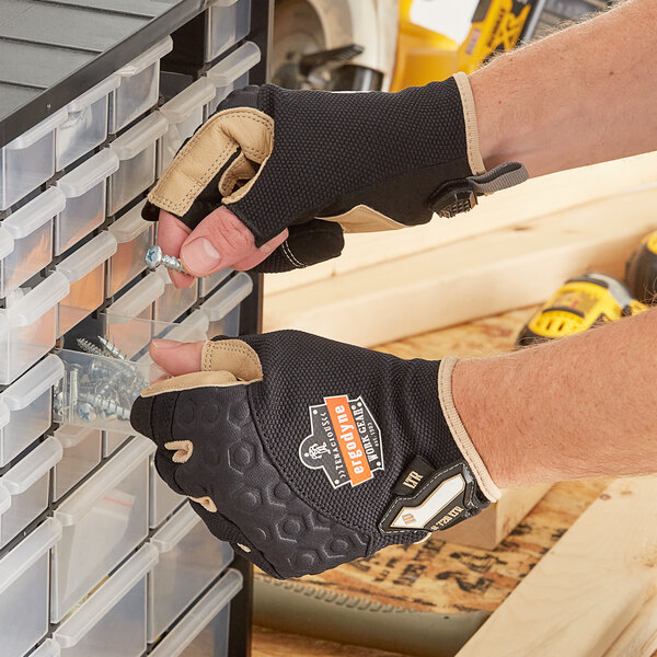 A person wearing Ergodyne heavy-duty leather-reinforced work gloves holding a screw in a drawer.