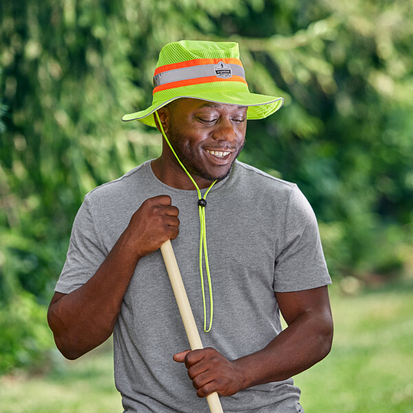 A man wearing an Ergodyne Lime Hi-Vis Ranger Sun Hat and holding a stick.
