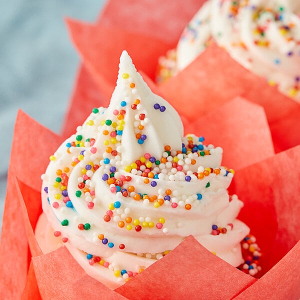A cupcake with white frosting and Rainbow Nonpareils on top.