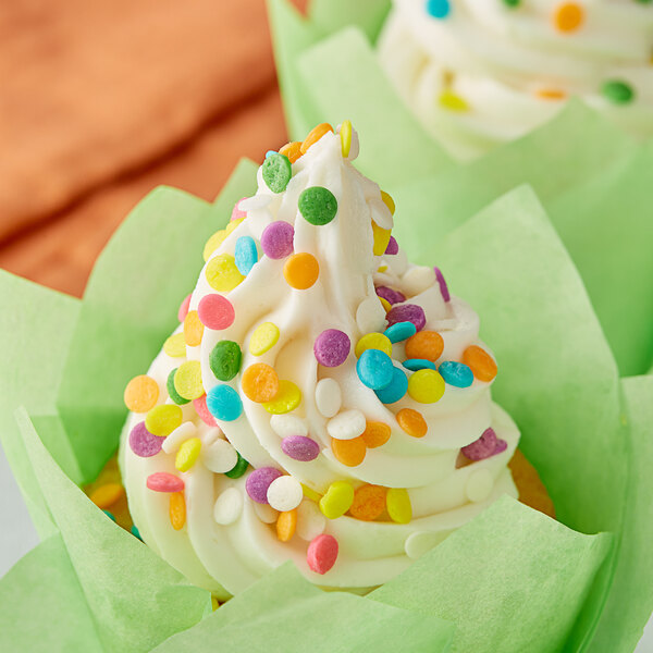 A close up of a cupcake with white frosting and Pastel Confetti Sequin Sprinkles.