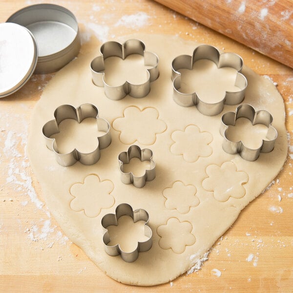 Ateco stainless steel cookie cutter set with flower shapes on cookie dough.