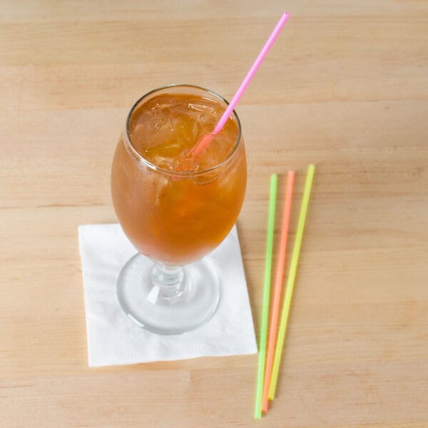 A glass of orange liquid with ice and a Choice neon sip straw.