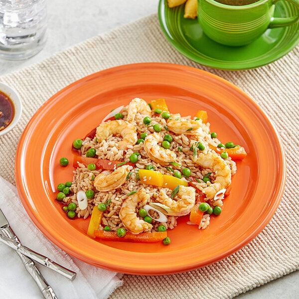 An Acopa Valencia Orange stoneware plate with a meal of rice, shrimp, and vegetables.