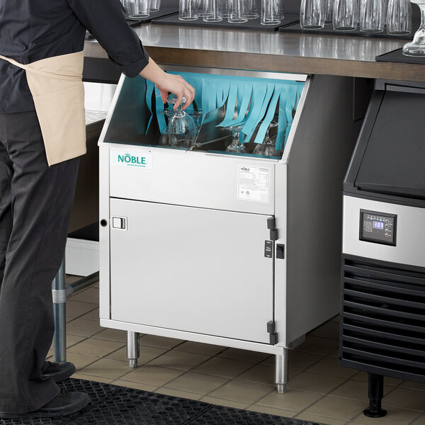 A commercial underbar glass washer with a carousel mechanism being used in a restaurant or bar setting.