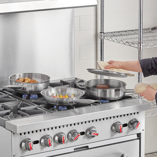 A woman cooking food in a silver Vigor stainless steel pot on a stove.