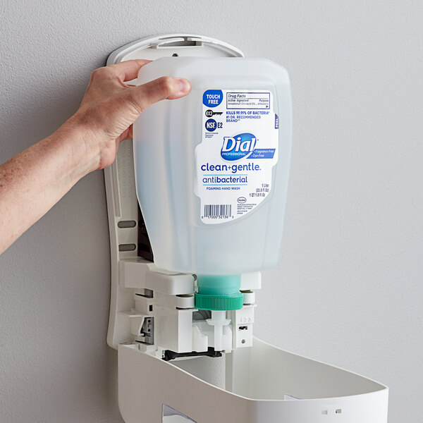 A hand holding a white plastic container of Dial Clean and Gentle foaming hand wash.