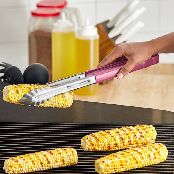 A person using purple Choice stainless steel scalloped tongs to serve corn on the cob.
