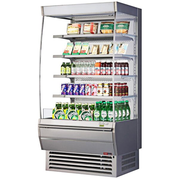 A Turbo Air stainless steel vertical display case with drinks and snacks.