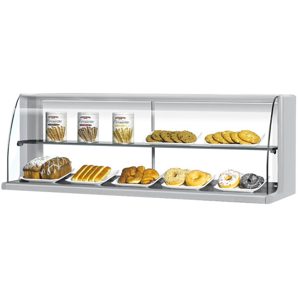 A Turbo Air stainless steel high profile top dry display case on a counter in a bakery with a variety of pastries on shelves.