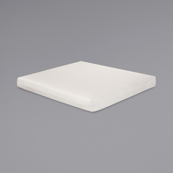A white square cushion on a gray surface.