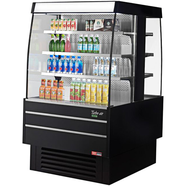 A black Turbo Air square island display case with drinks on shelves.