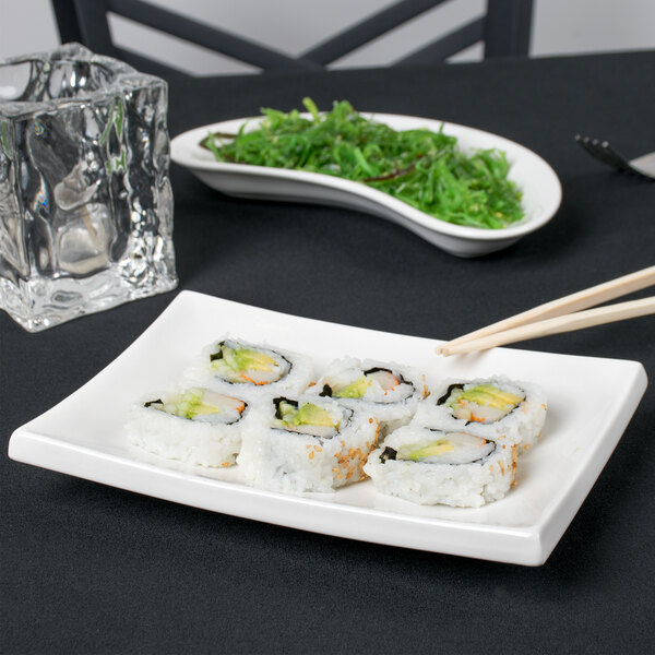 A CAC rectangular porcelain platter with sushi and chopsticks on a table.