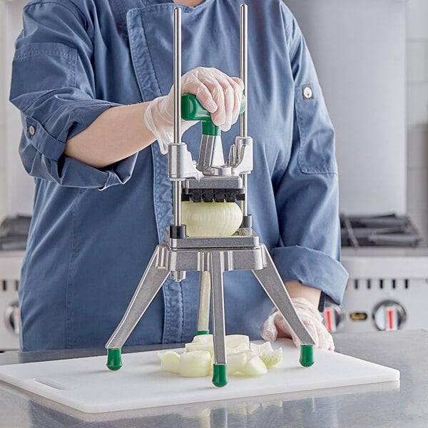 A woman in a blue uniform using a Garde DC1 Heavy-Duty Vegetable Dicer to cut onions.