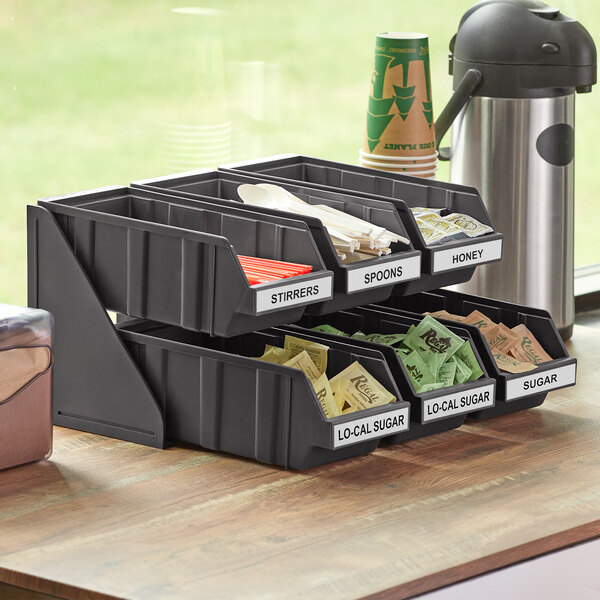 A black plastic Choice 2-tier tray with bins and labels on a counter.