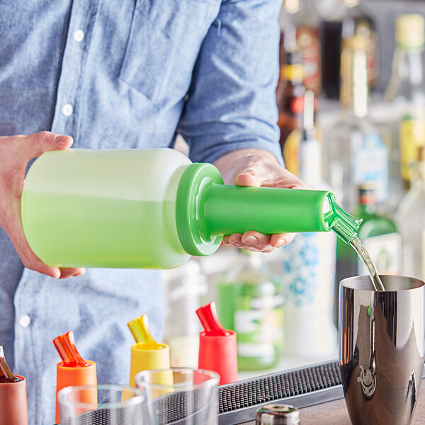 A person using a Choice green neck pour bottle to pour liquid into a cup.